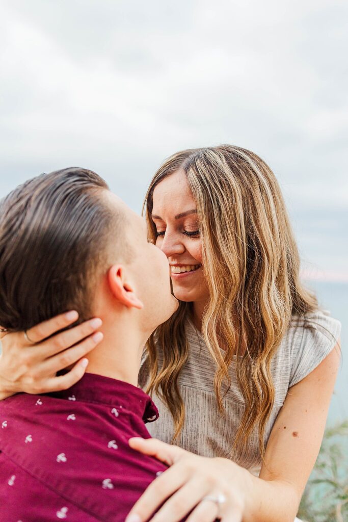 Couple hugging after proposal overlooking Lake Michigan