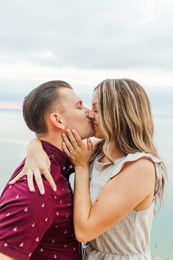 Couple hugging after proposal overlooking Lake Michigan