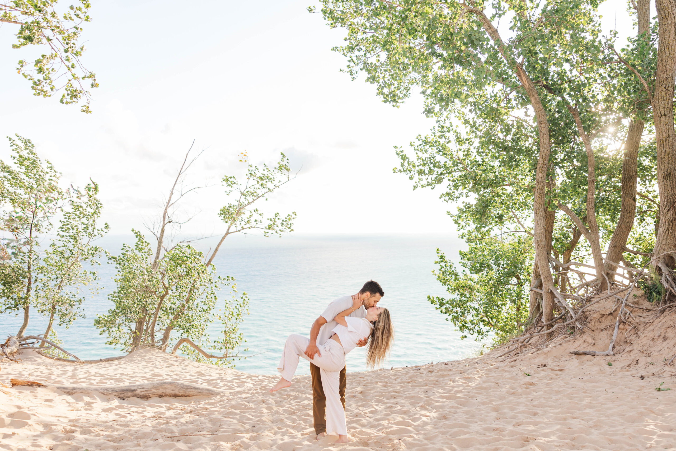 Engaged couple sharing a kiss at the overlook on Pierce Stocking Drive with Sleeping Bear Dunes and Lake Michigan in the background