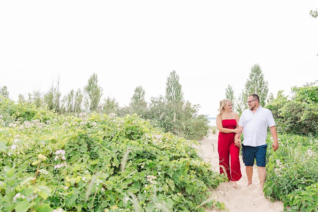 Couple smiling together in a tree-lined area during their Elk Rapids engagement session