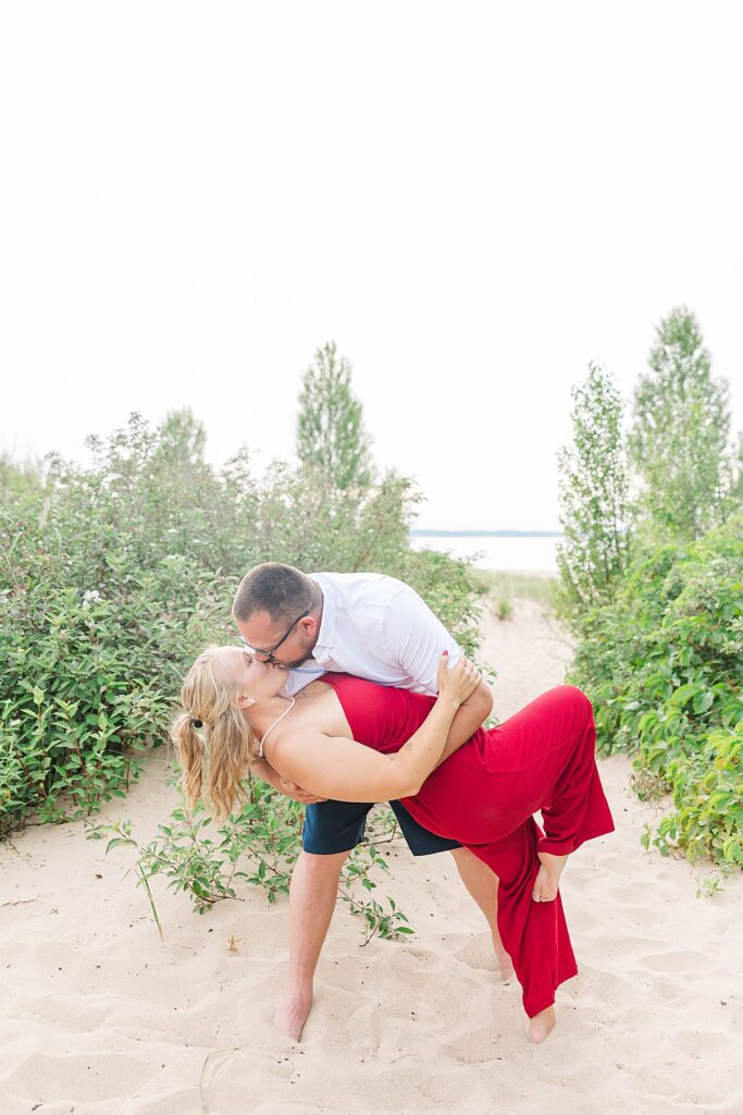 Engagement photos in Elk Rapids with the couple framed by lush green trees