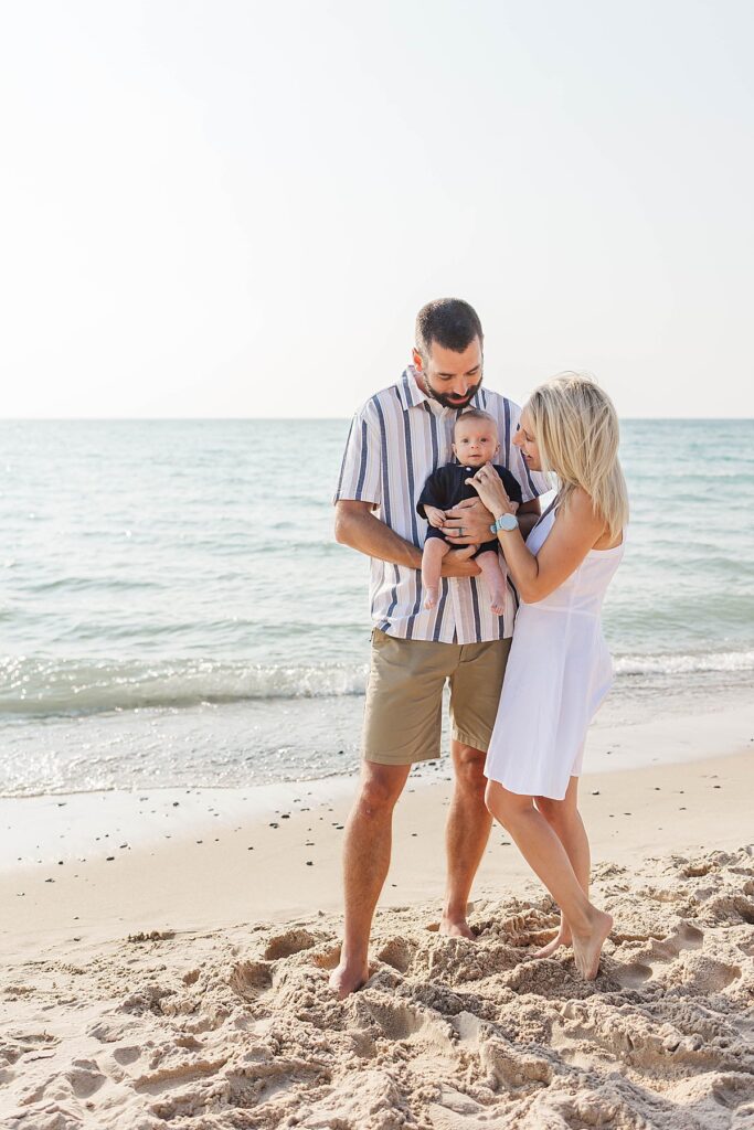 Newborn wrapped in parent’s arms at Empire Beach in Northern Michigan