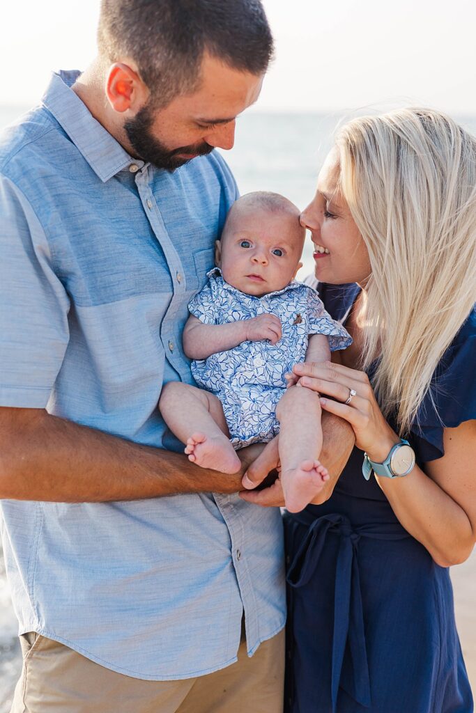 Parents snuggling their newborn during a beach family session