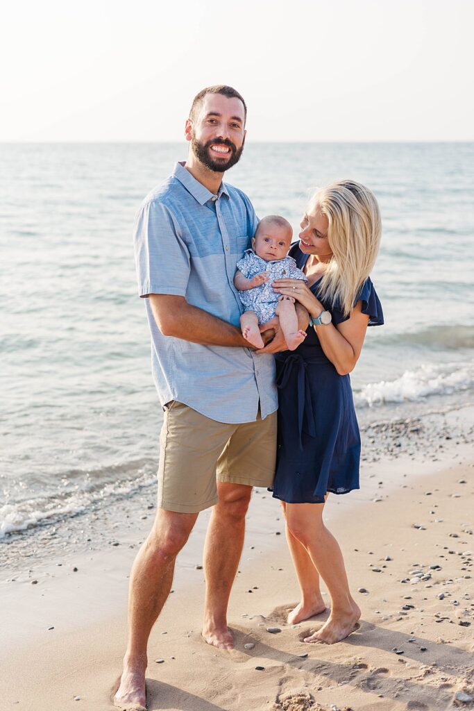 Newborn wrapped in parent’s arms at Empire Beach in Northern Michigan