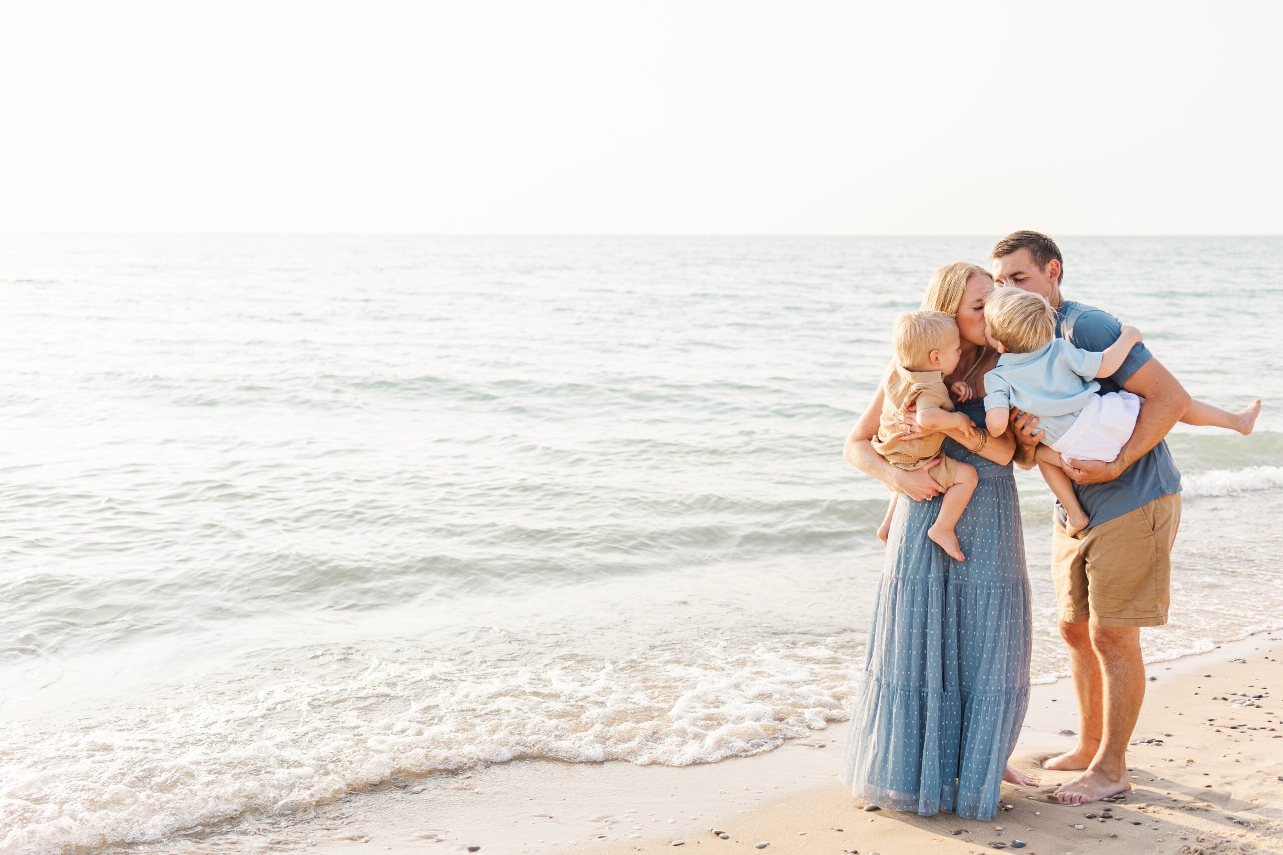 Family sharing a sweet moment on the shore at Empire Beach in Northern Michigan during their family photo session