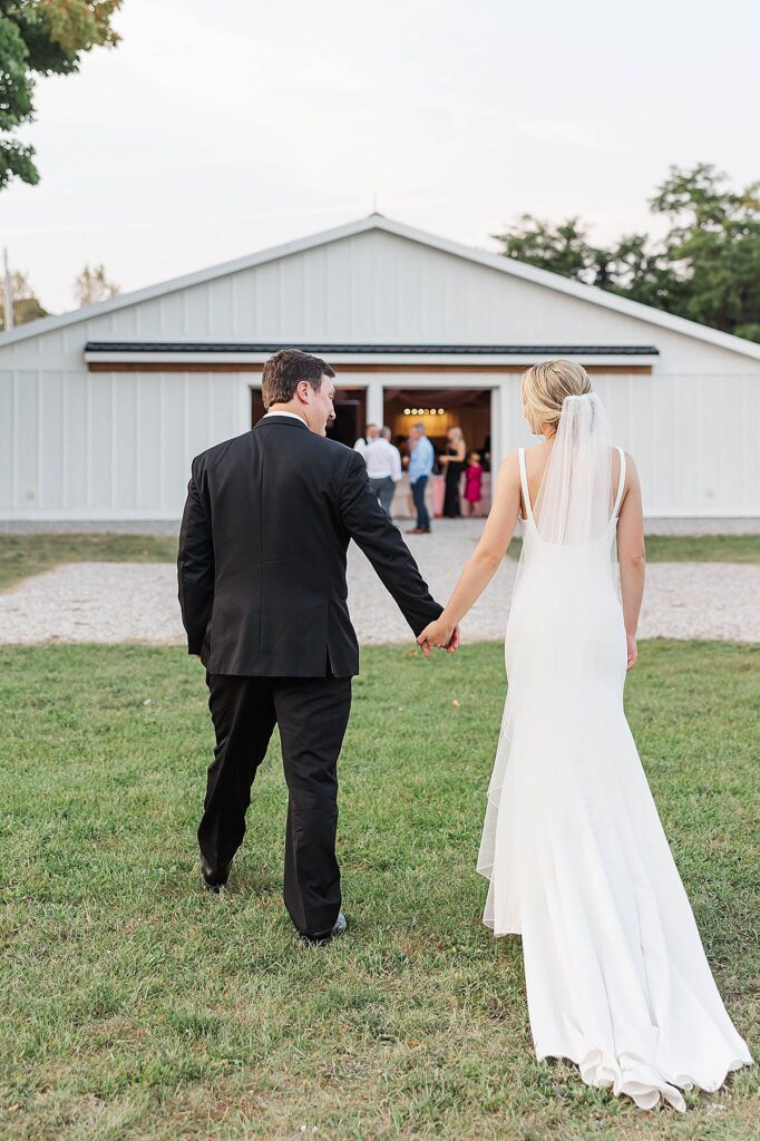 Bride and groom walking back to Mill Pond Event Center after sunset portraits