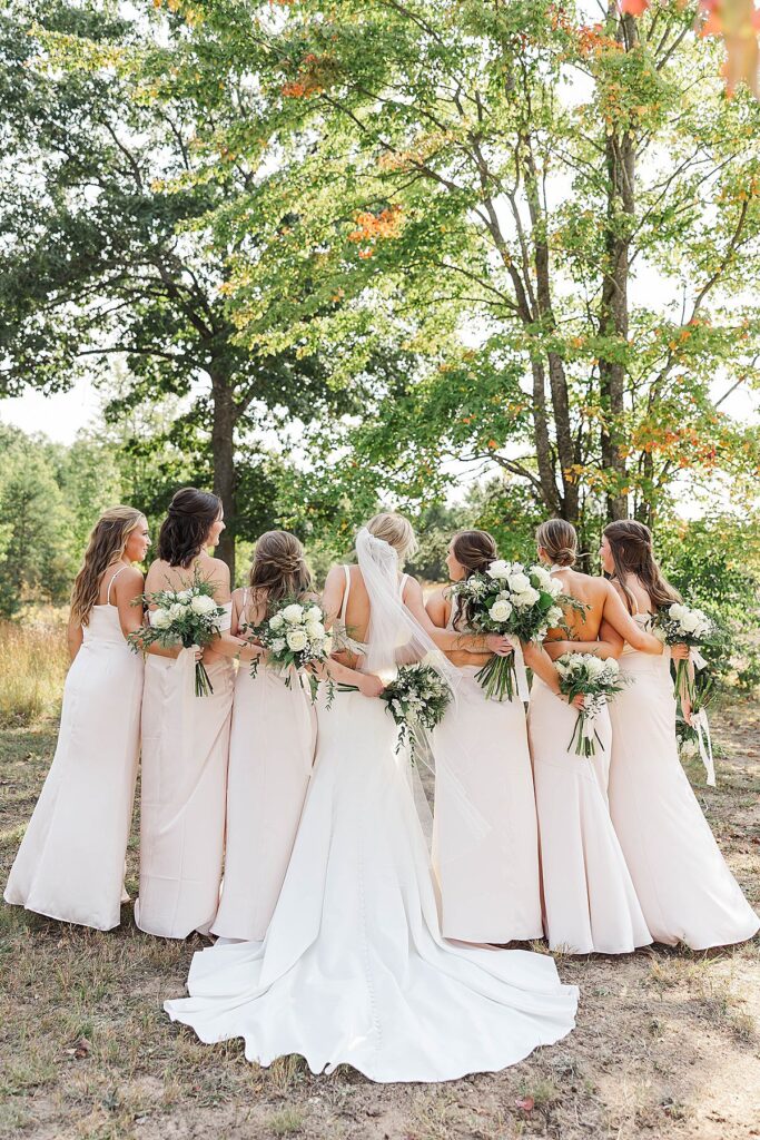 Bride and bridesmaids from behind holding fall wedding florals in Northern Michigan