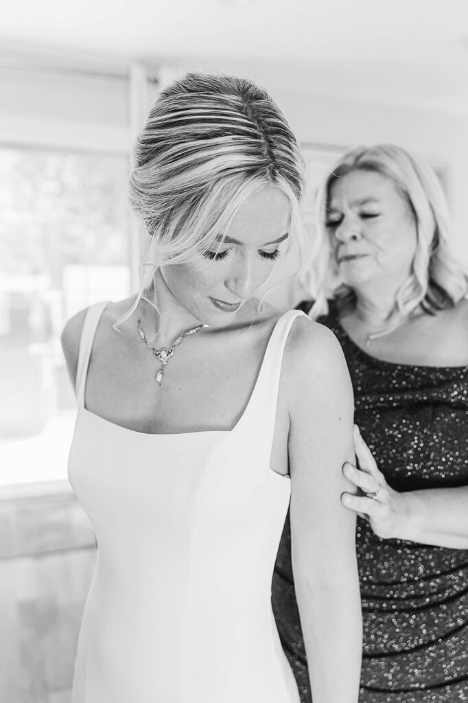 Bride’s mother helping her into her wedding dress before the ceremony