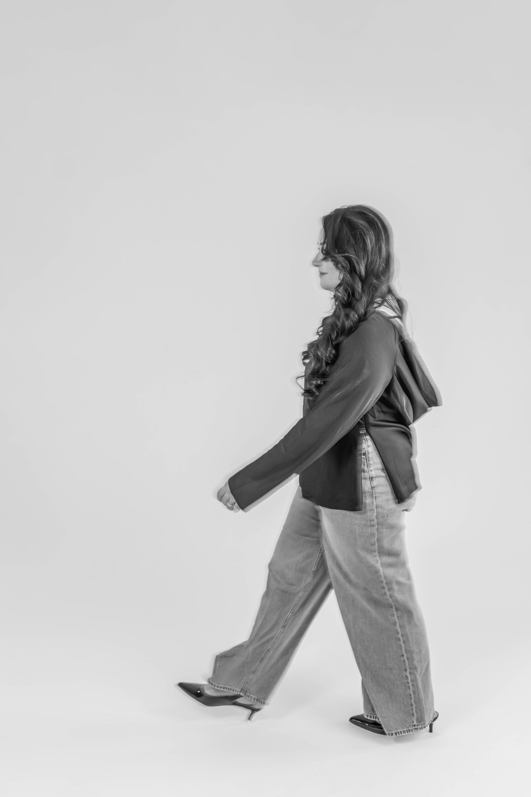 Black and white photo of a photographer walking confidently during a branding session in Traverse City, Michigan