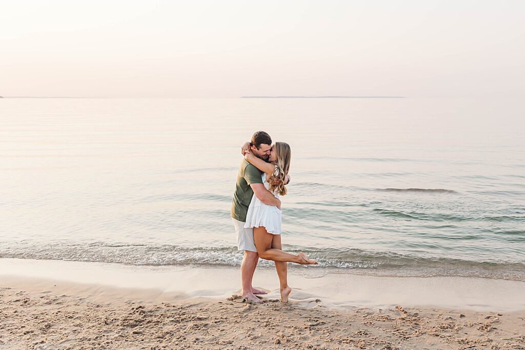 Intimate Northern Michigan engagement photos of a couple embracing by Lake Michigan