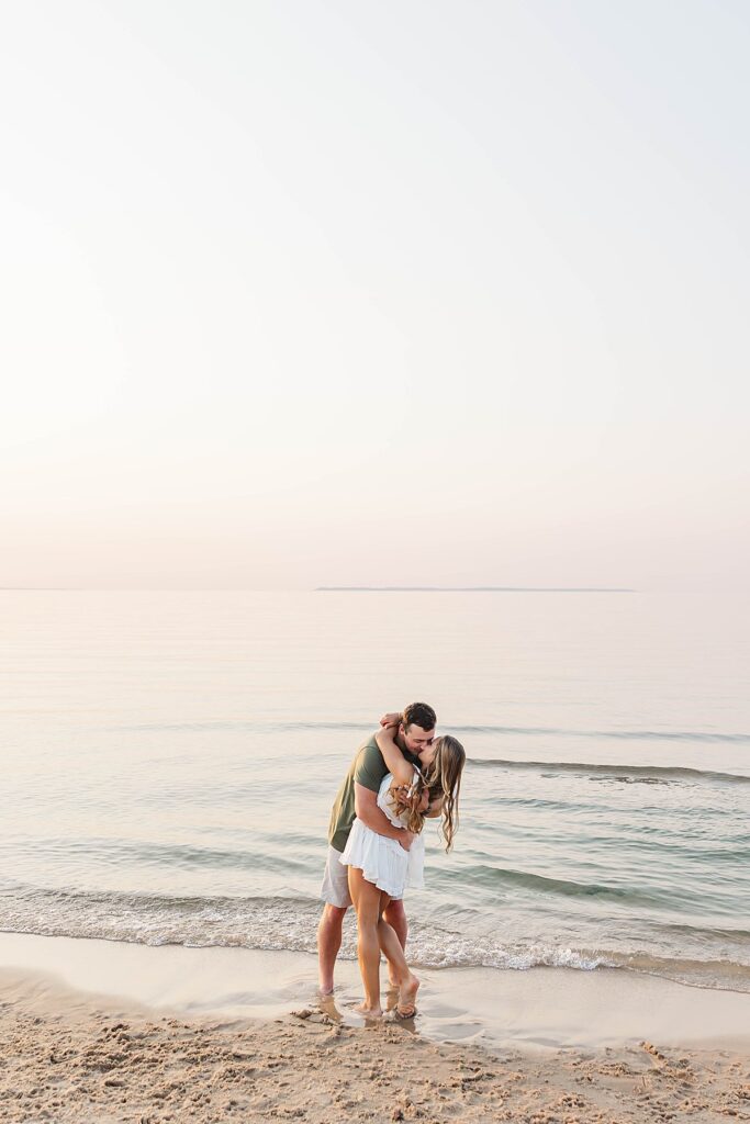 Golden-hour Northern Michigan beach engagement session with a joyful couple