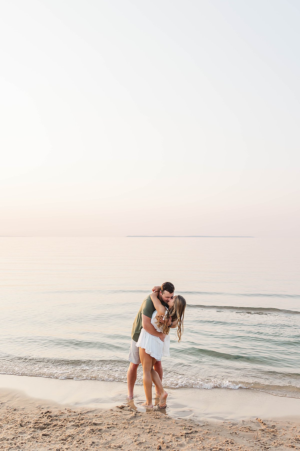 Couple embracing during a Northern Michigan beach engagement session at sunset