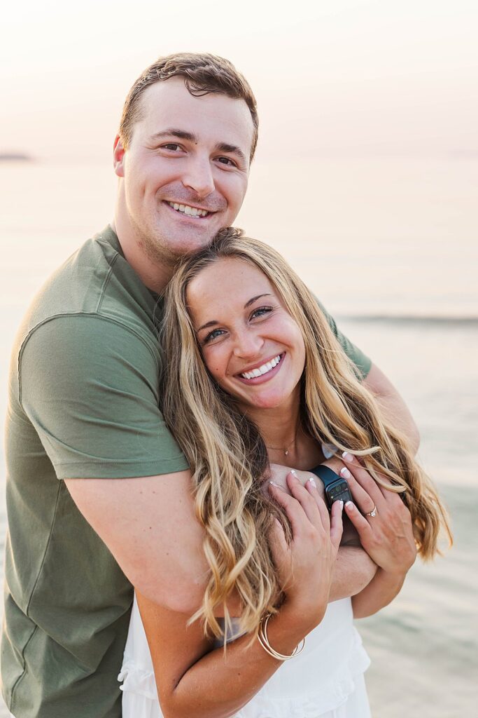 Romantic Northern Michigan beach engagement photos with calm water and soft light
