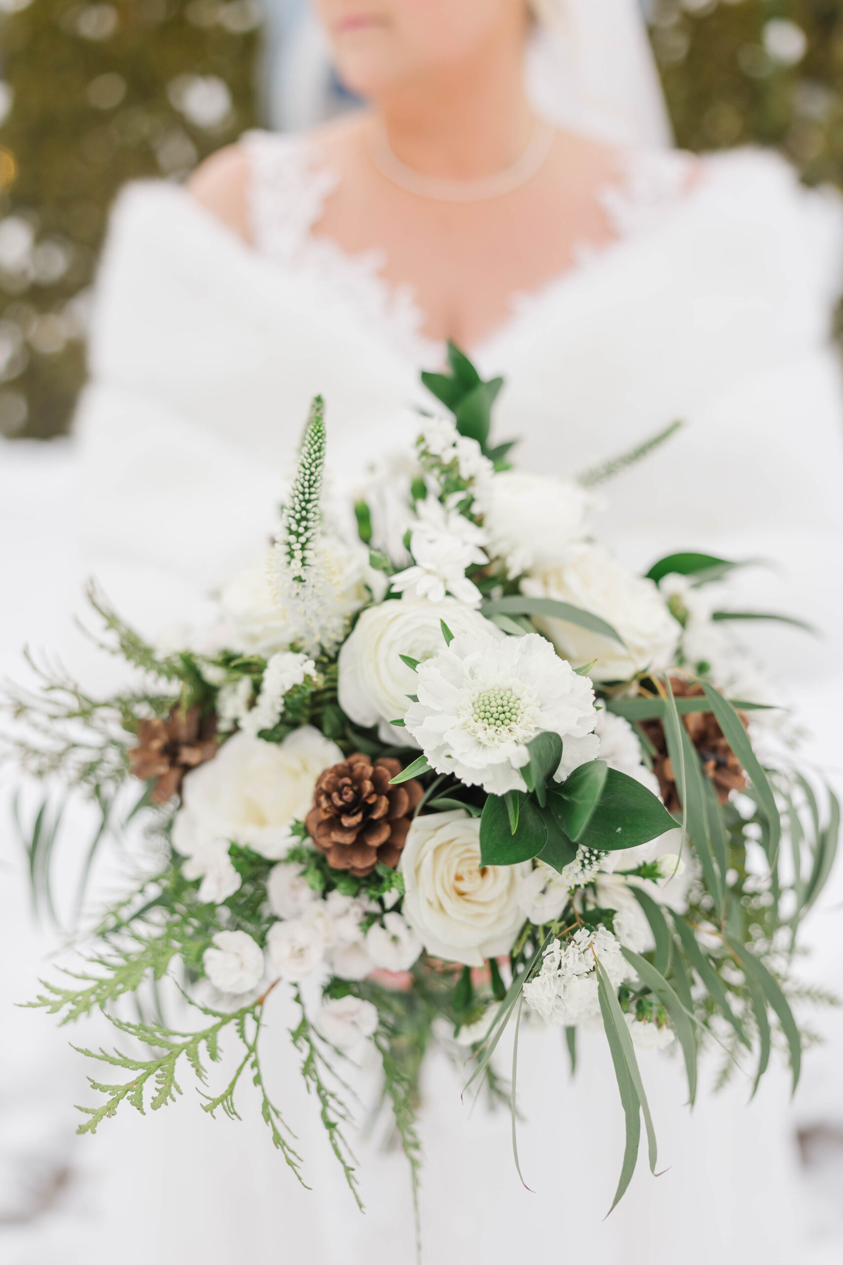 Close-up of a winter bridal bouquet with white flowers, pinecones, and greenery at Patrick & Christy’s Greystone Weddings celebration near Traverse City, Michigan