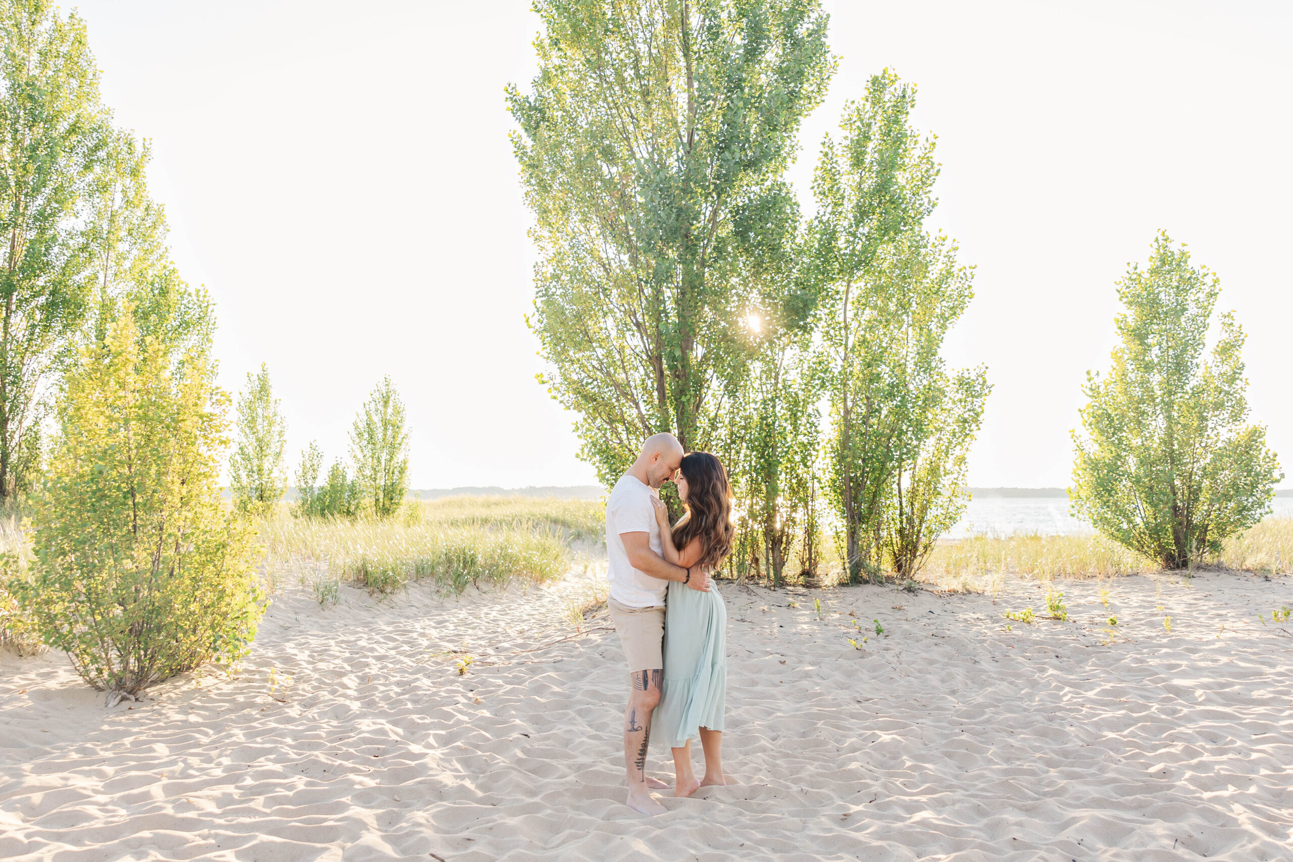 Parents sharing a quiet, loving moment during their family and newborn session at The Dam Beach on Elk Lake in Northern Michigan