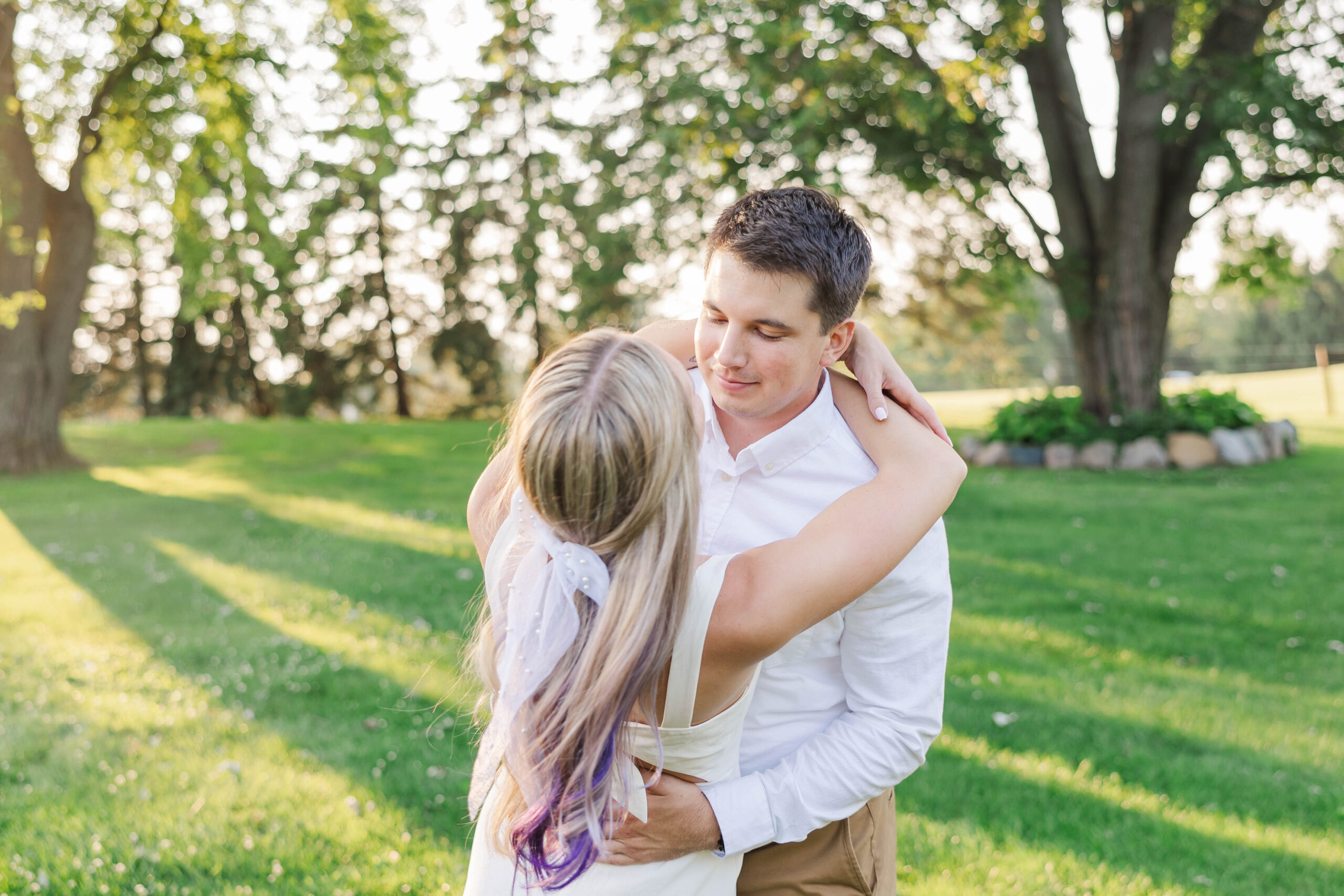 Engaged couple sharing a quiet moment together in a sunny Northern Michigan field during their engagement session