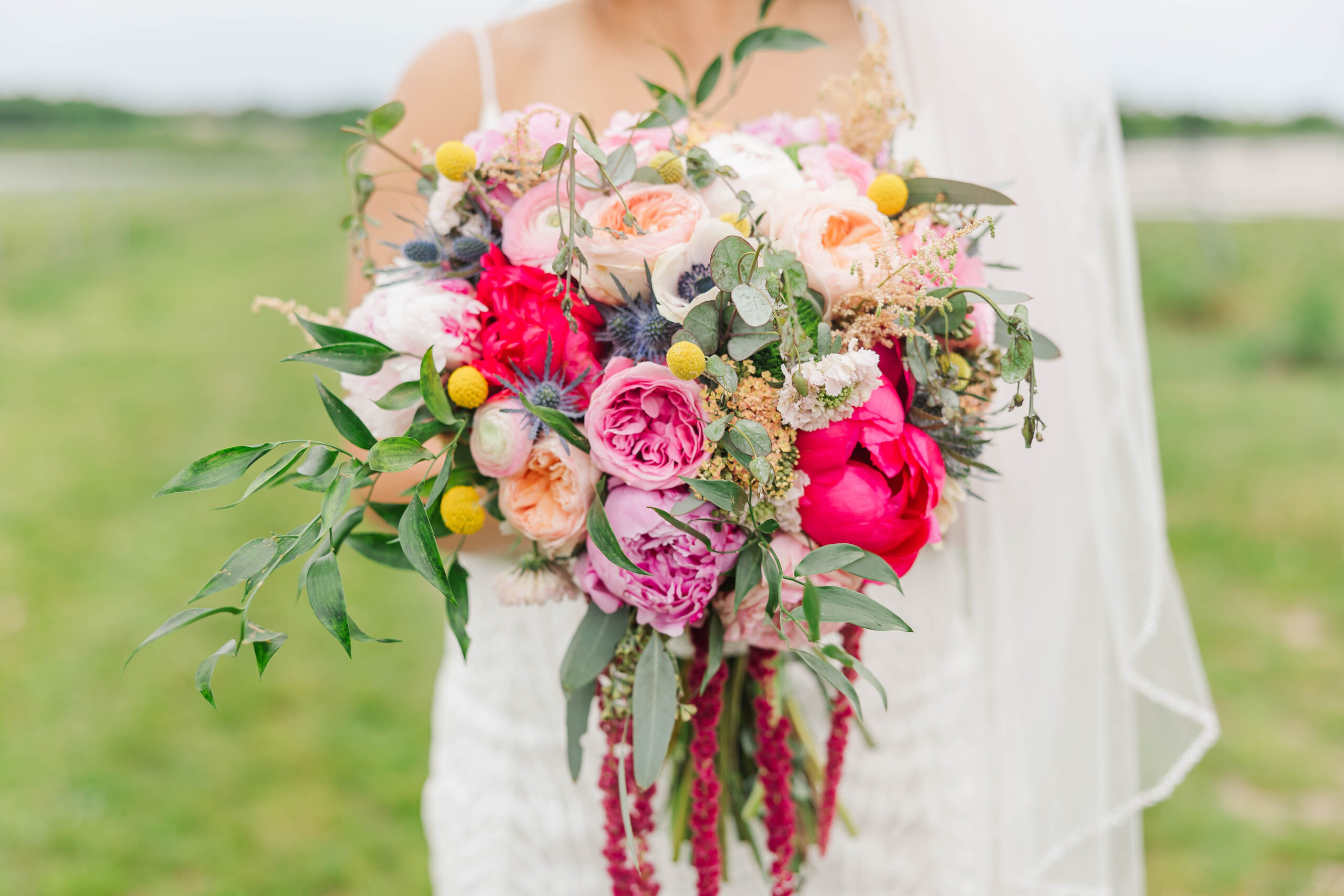 Bride holding a vibrant, colorful wedding bouquet with pink, peach, and yellow florals at a Traverse City, Michigan wedding