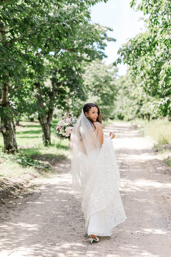 Bride walking through the orchard at Gallagher Farms during a Bayview wedding