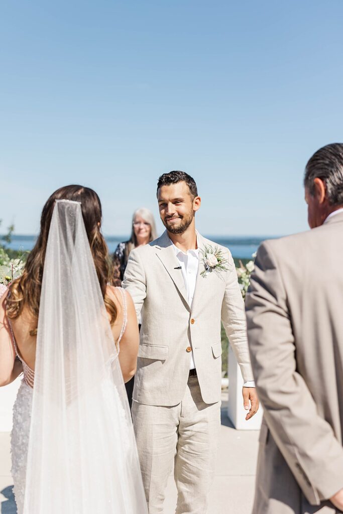 Couple exchanging vows at Bayview Weddings at Gallagher Farms with Grand Traverse Bay behind them