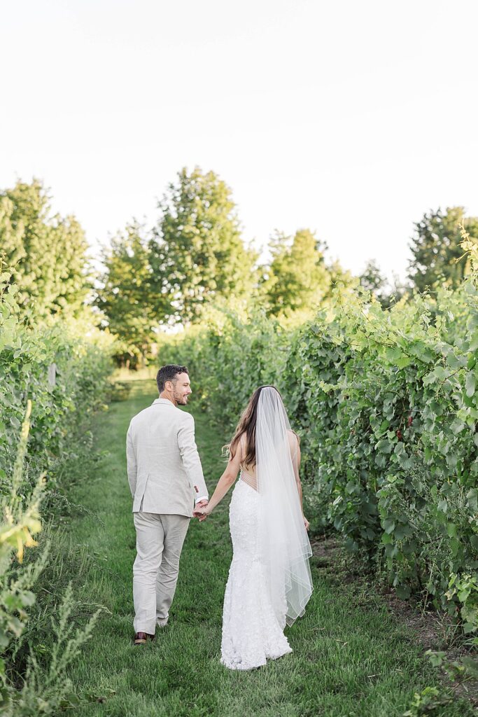 Bride and groom walking through the vineyard at Gallagher Farms during a Bayview wedding