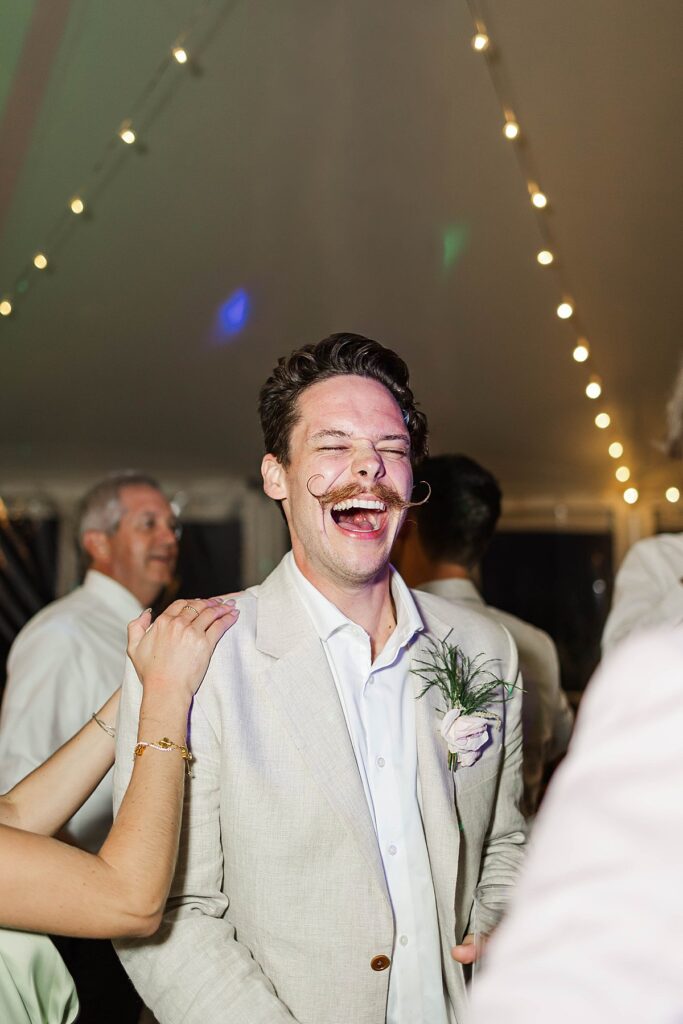 Groom laughing on the dance floor during a Bayview wedding reception at Gallagher Farms
