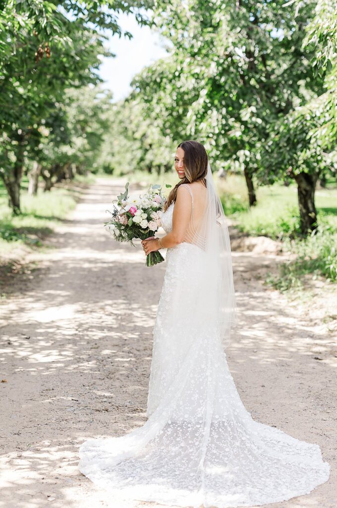 Bride walking through the orchard at Gallagher Farms during a Bayview wedding in Northern Michigan