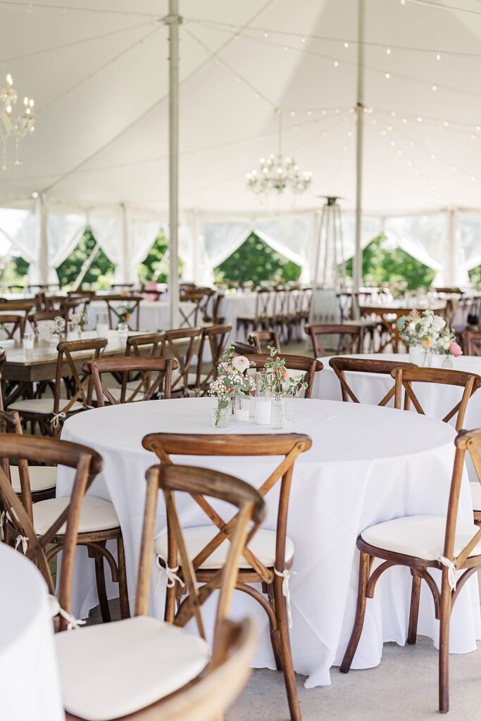 Elegant Bayview wedding reception tables at Gallagher Farms with wooden chairs, white linens, and floral centerpieces