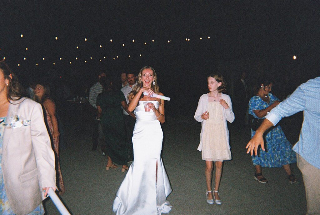 Wedding guests celebrating during an outdoor barn reception, disposable camera photo