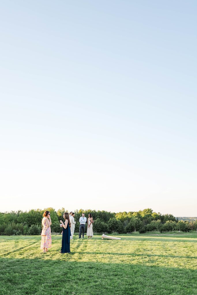 Guests mingling and playing lawn games during sunset at Bayview Weddings at Gallagher Farms