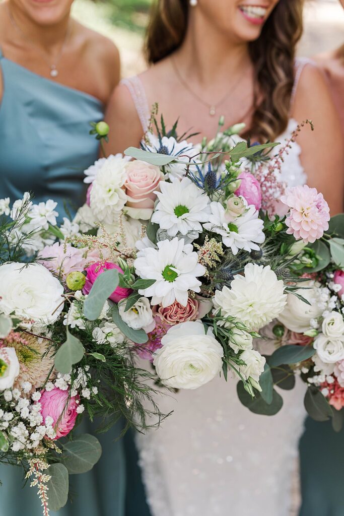 Bride and bridesmaids holding colorful wedding bouquets at Bayview Weddings at Gallagher Farms
