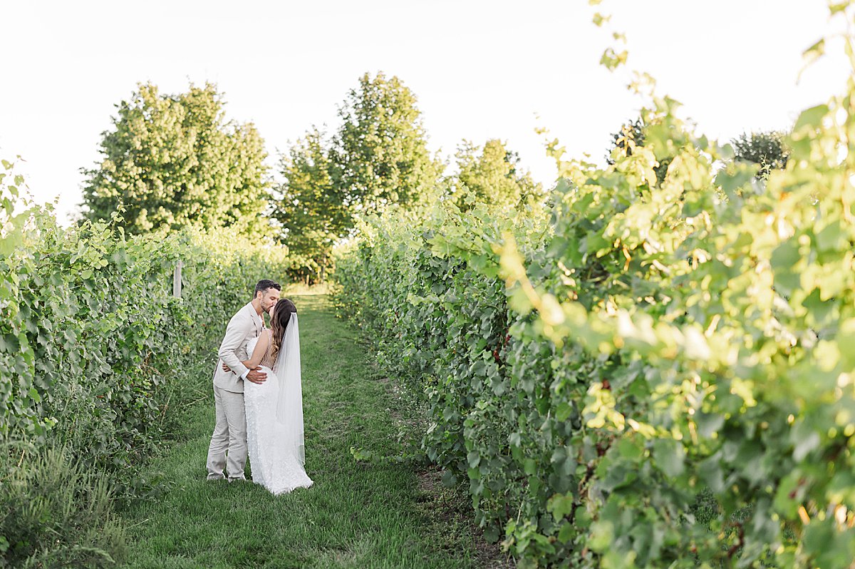 Couple kissing in a vineyard at sunset at Bayview Weddings at Gallagher Farms overlooking Grand Traverse Bay
