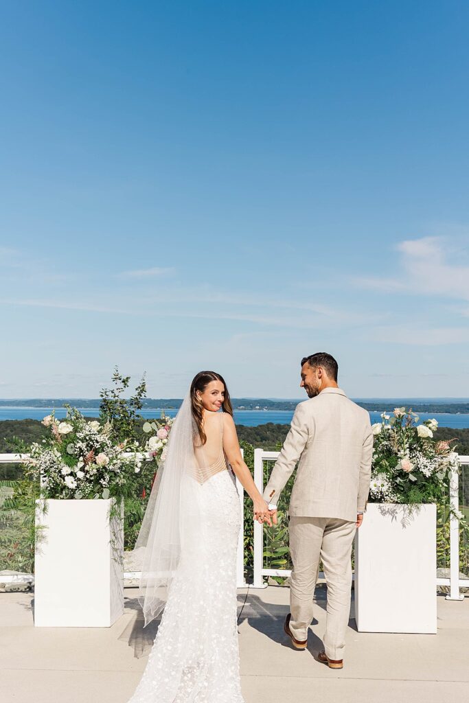 Bride and groom walking between ceremony florals at the Bayview Weddings overlook