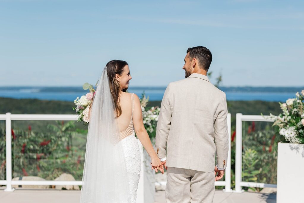 Bride and groom holding hands at Bayview Weddings at Gallagher Farms in Cedar, Michigan overlooking Grand Traverse Bay during a luxury Northern Michigan wedding.