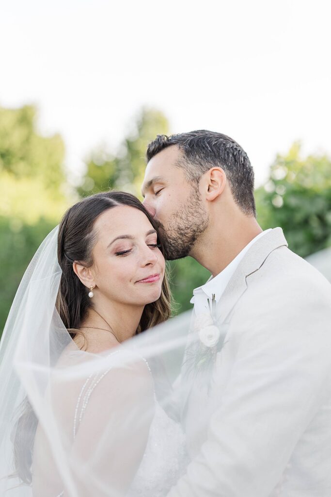 Bride and groom embracing at Bayview Weddings at Gallagher Farms in Cedar, Michigan during a luxury Northern Michigan vineyard wedding.