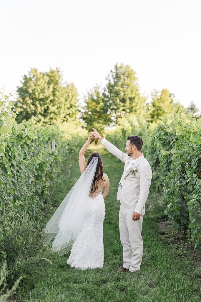 Couple walking through vineyard rows on Old Mission Peninsula during a Northern Michigan engagement session