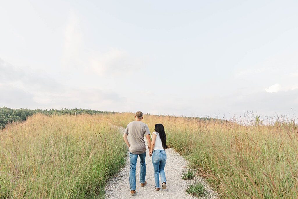 couple walking through rolling fields at Brown Bridge Quiet Area during a Northern Michigan portrait session