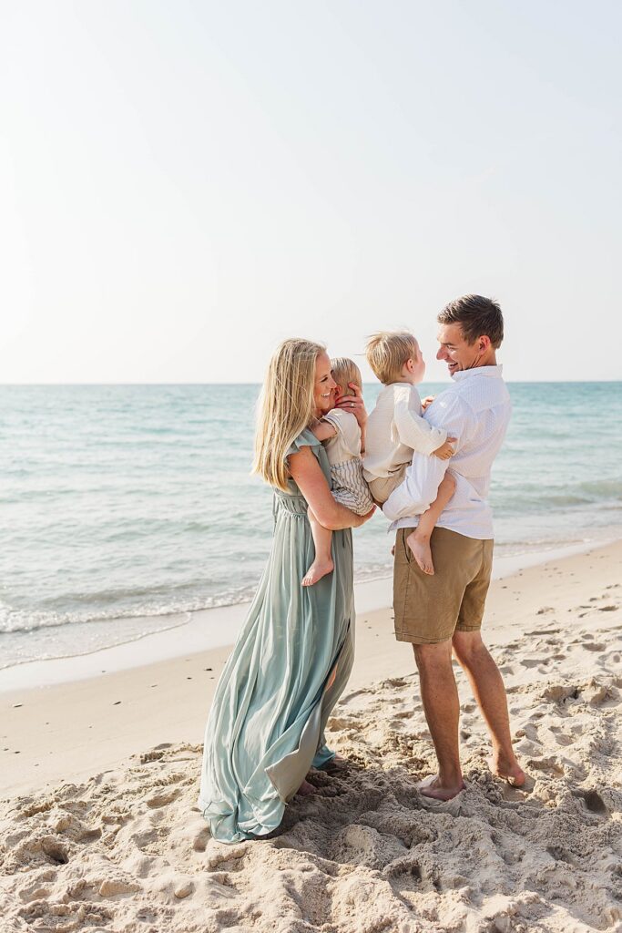 Northern Michigan beach family portrait session with parents holding two young children near Lake Michigan