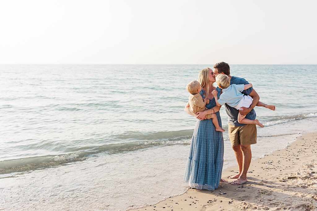 family with two kids walking along the shoreline at Empire Beach during a Northern Michigan portrait session