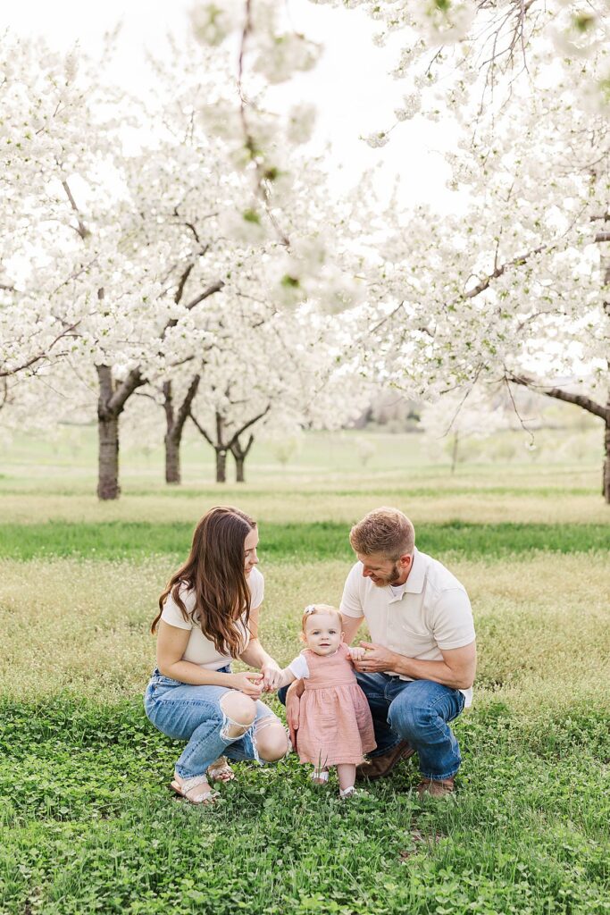 Northern Michigan family portrait session with parents and baby under cherry blossom trees