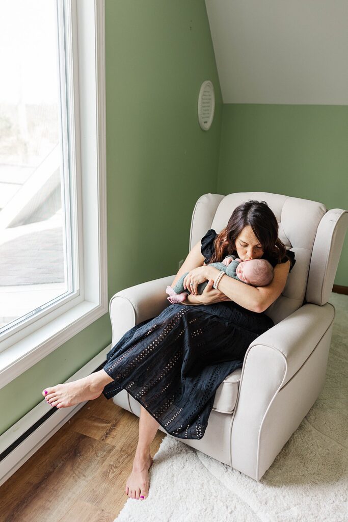 mom kissing newborn baby during an in-home Northern Michigan portrait session