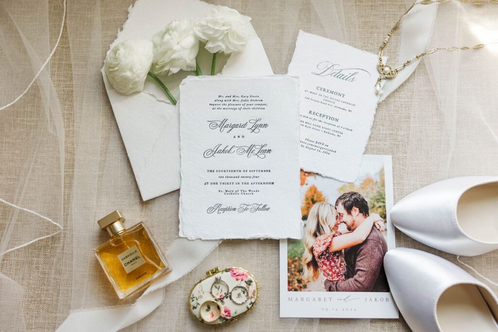 northern Michigan wedding detail photos flat lay with invitation suite, rings, ribbon, and florals