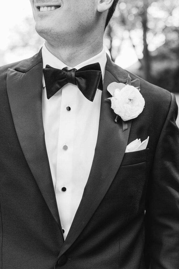 black and white groom detail photo showing bow tie, boutonniere, and suit for wedding detail photos