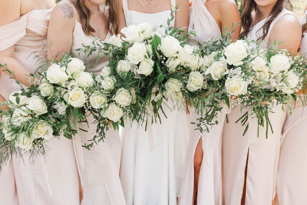 bride and bridesmaids holding bouquets together during a candid wedding moment