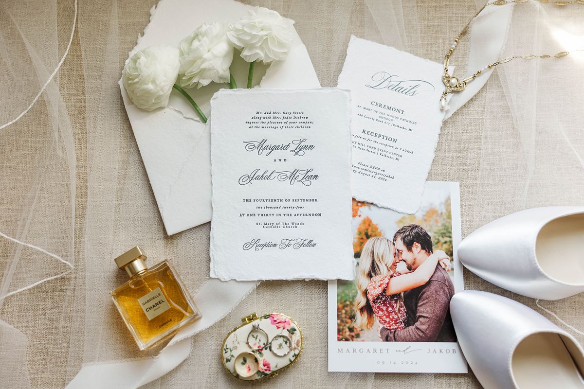 northern Michigan wedding detail photos flat lay with invitation suite, rings, ribbon, and florals