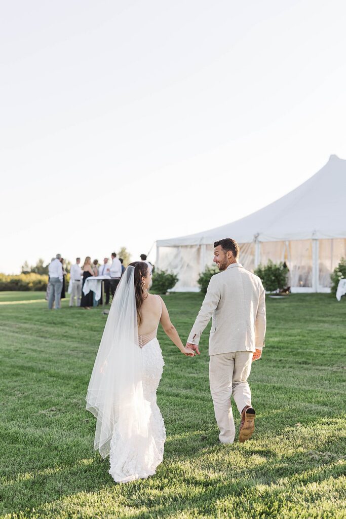 Bride and groom walking toward their Northern Michigan wedding reception tent