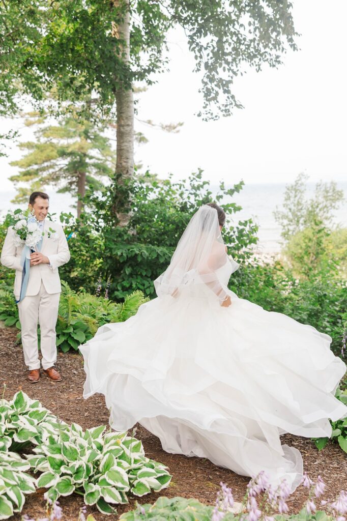 Bride twirling during an emotional first look while groom watches at The Perry Hotel wedding in Petoskey, Michigan