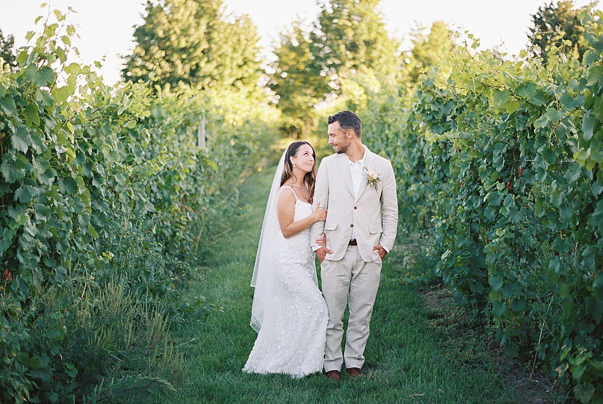Couple walking through a vineyard during a Northern Michigan wedding weekend celebration