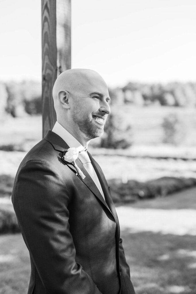 Groom smiling as he watches his bride walk down the aisle at a Lavender Hill Farm wedding