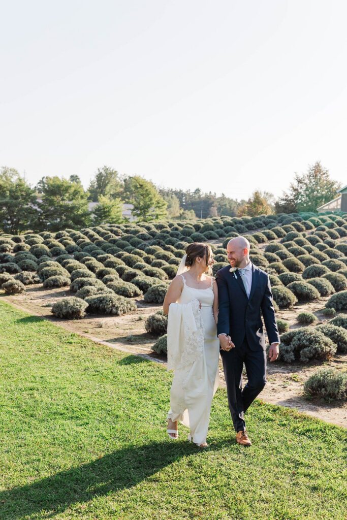 Bride and groom walking through the lavender fields after their Lavender Hill Farm wedding ceremony