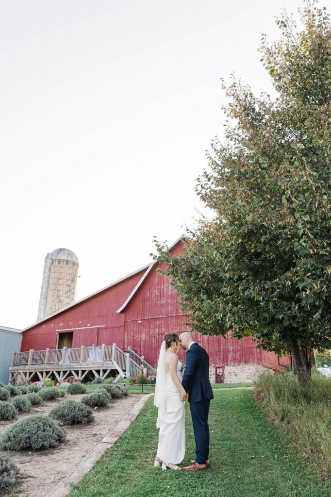 Bride and groom holding hands in front of the red barn at Lavender Hill Farm after their wedding ceremony